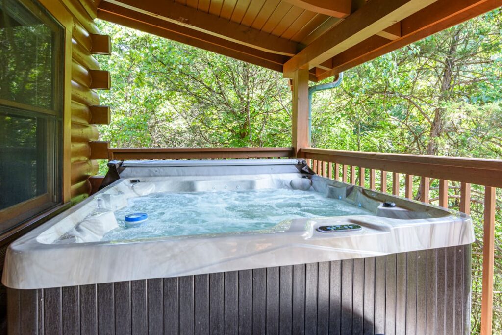 Private hot tub on the wooded covered deck at American Way Cabin