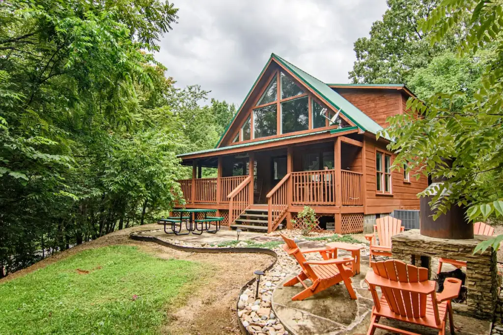 The Moonshine Cabin surrounded by trees with porch and outdoor seating